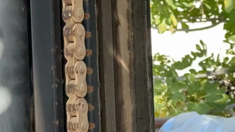 Chain and rust on a metal frame with green leaves in background Stock Footage 324811291