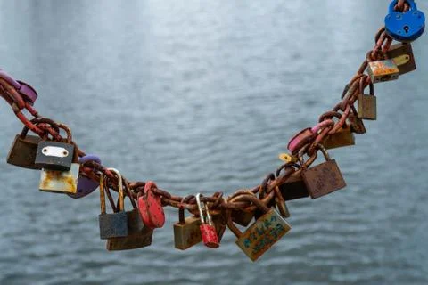 Chain on a bridge over a river with locks of lovers Stock Photos