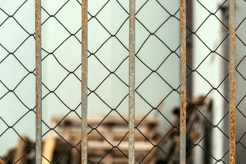 Chain link diamond pattern wire fence and worn metallic bars Stock Photos