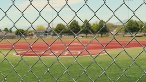 Chain Link Fence in Focus With Blurred Baseball Field Background Stock Footage 336804500