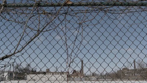 Chain link fence in foreground of parking lot in inner city winter Stock Footage