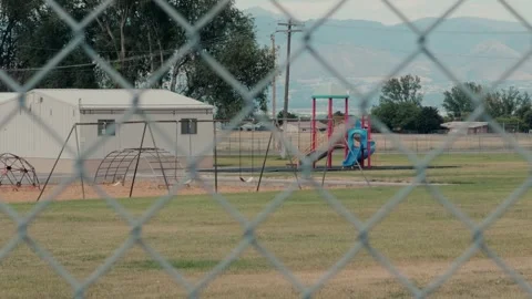Chain Link Fence Framing Playground and Relocatable Building in Public Park Stock Footage 340548057