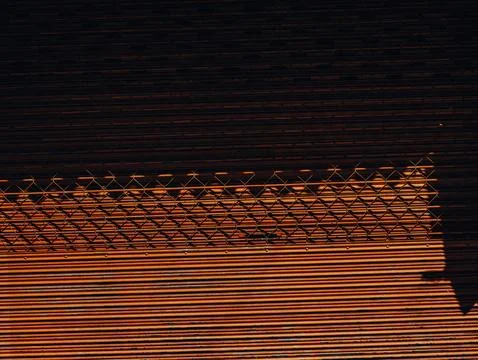Chain Link Fence Shadow Pattern on Rusty Orange Metal Shutter, Warm Light A.. Stock Photos
