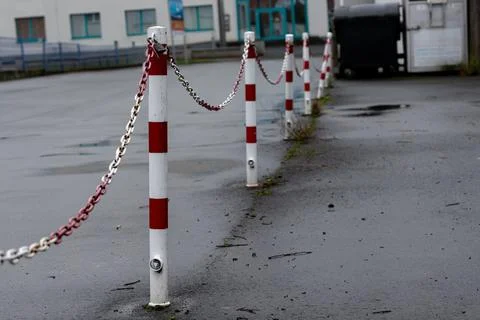 Chain-linked posts line a wet surface in an empty parking area Stock Photos