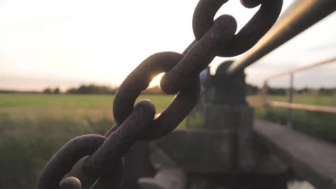Chain links passing through frame at sunset Stock Footage 291883054