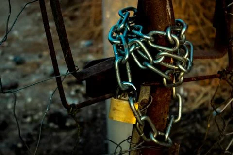 The chain with the lock locks the old, rusty gate Stock Photos
