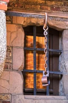 A chain from an old prison in front of the bars. Stock Photos