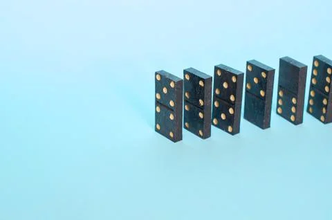 A chain of playing dominoes on a solid blue background Stock Photos