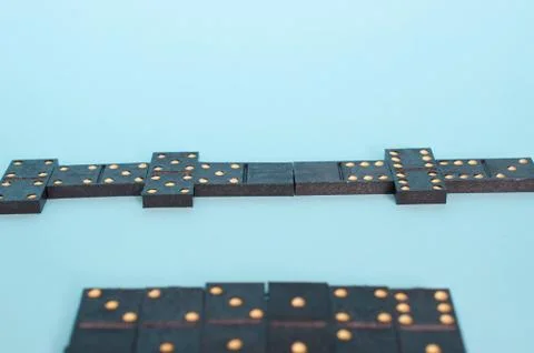 A chain of playing dominoes on a solid blue background Stock Photos