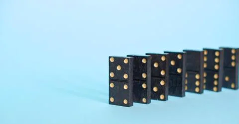 A chain of playing dominoes on a solid blue background Stock Photos
