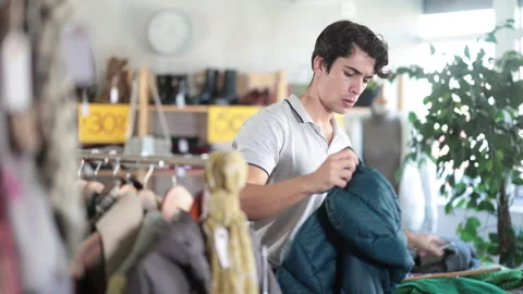 In chain shop, guy choose down jacket Stock Footage 327700228