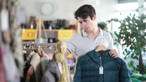 In chain shop, guy choose down jacket Stock Footage 341381428