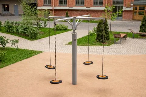 Chain swing carousel with suspended round seats in courtyard playground. Gi.. Stock Photos