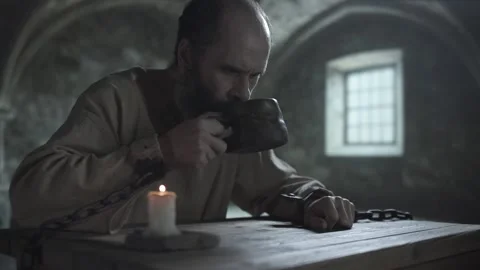 Chained cell inmate taking a sip from a clay cup and putting it back Video stock 337648858
