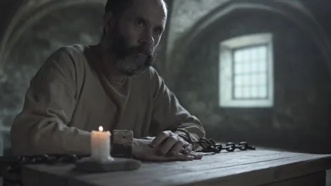 Chained dungeon prisoner scratching his hand, raising an alarmed look aside Vídeo Stock 340322487