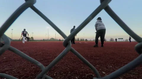 Chained Fun, A slider shot of a softball game behind the backstop Stock Footage 48670032