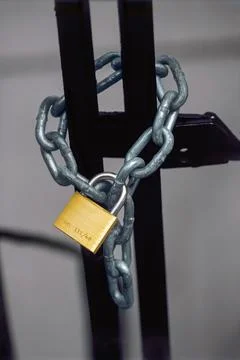 Chained gate secured by a brass padlock Stock Photos