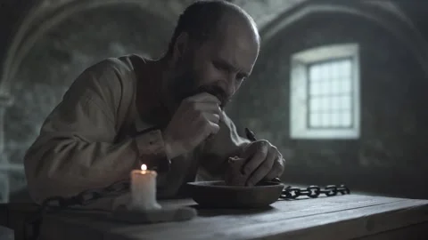 Chained inmate breaking bread over a bowl and eating a piece at a table Stock Footage 338991682