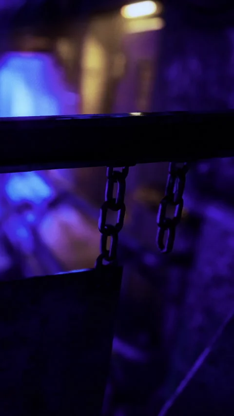 Chained links hang in a dimly lit space during nighttime activity 스톡 동영상 331756412