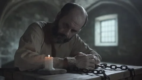 Chained prisoner blowing out a burning candle and staring at a smoking wick Video stock 340322862