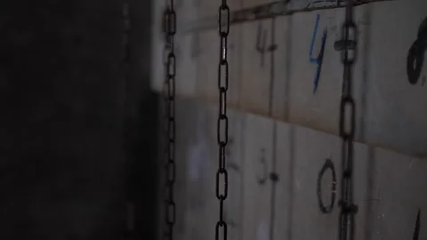 The chains are hanging on a gray wall with numbers and dashes in the quest room. Stock Footage 310655756