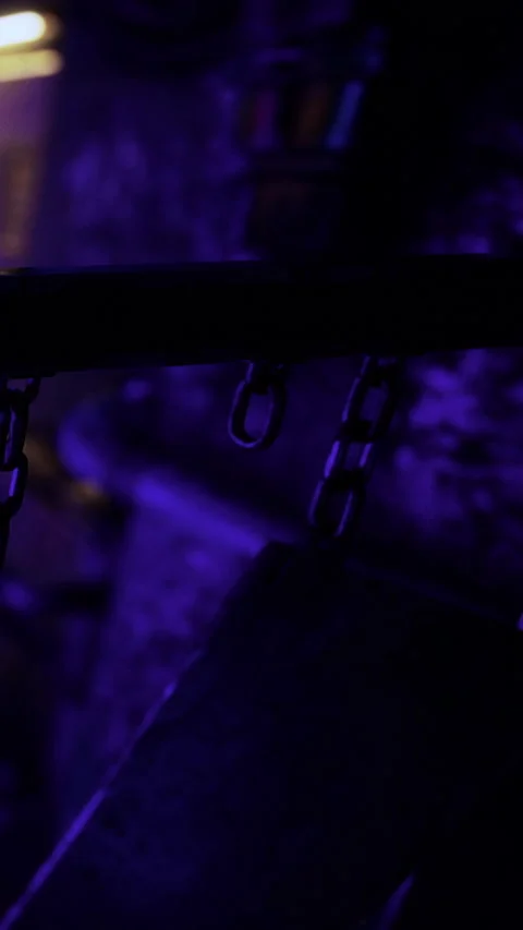 Chains hanging in a dark space with purple light at a location Stock Footage 331753315