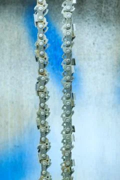 Chainsaw blade chain close-up on the background of the old wall in the garage Stock Photos