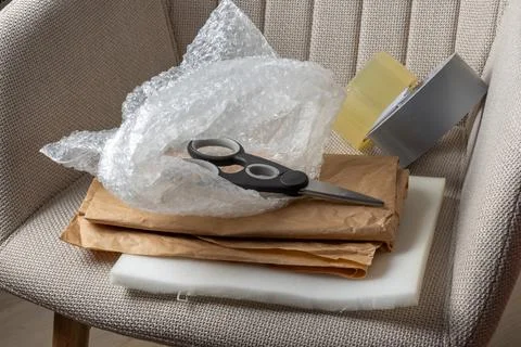 A chair with bubble wrap, scissors, and packing materials ready for a move. Stock Photos