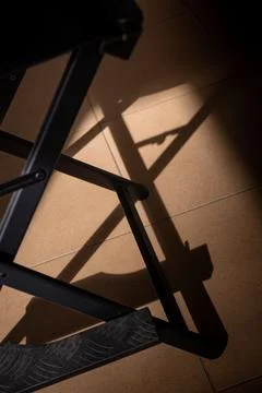 Chair casting geometric shadow on tiled floor Stock Photos
