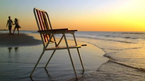 Chair on the coast in sunset with backgrounf of people silhouettes Vídeo Stock 59348062