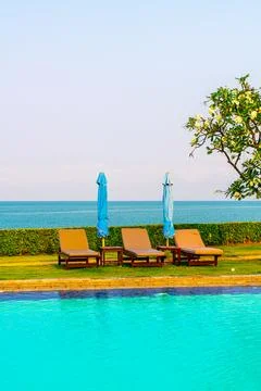 Chair pool  or bed pool and umbrella around swimming pool with sea background Stock Photos