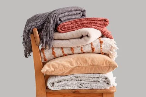 Chair with stack of plaids and pillow on light background Fotos de archivo