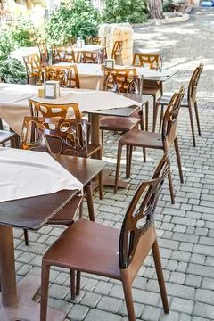 Chairs and empty tables in open air restaurant in summer Stock Photos