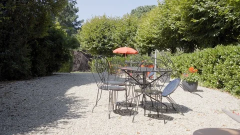 Chairs and table on dirt road amidst trees Stock Footage 101627963