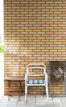 Chairs and table in front of a brick wall. Stock Photos