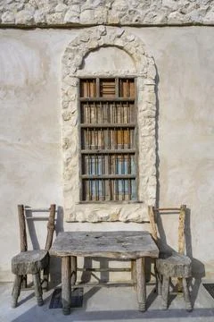 Chairs and a table made of rough wood on the street under an arched window Stock Photos