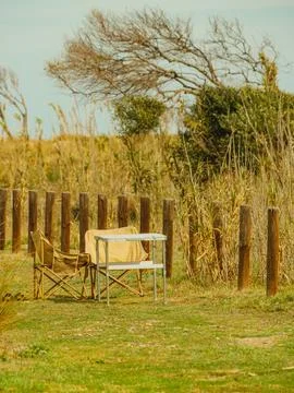 Chairs are placed by a small table in a grassy area. Wooden posts outline the Stock Photos