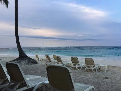 Chairs Lined up on a Tranquil Beach at Sunset With Gentle Ocean Waves Stock Photos