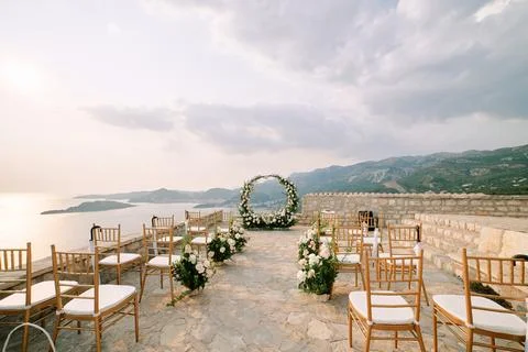 Chairs stand in rows in front of a round wedding arch on an observation deck in 스톡 사진