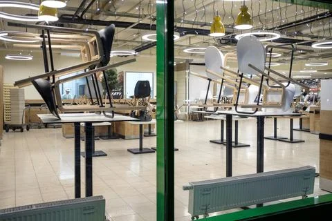 Chairs on a table in an empty mall restaurant after work is completed. Stock Photos