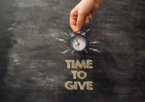 Chalk text time to give on black school board.  Stock Photos