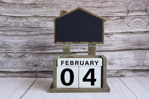 Chalkboard with date on white cube block on wooden table. Stock Photos