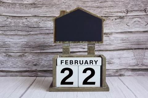 Chalkboard with date on white cube block on wooden table. Stock Photos