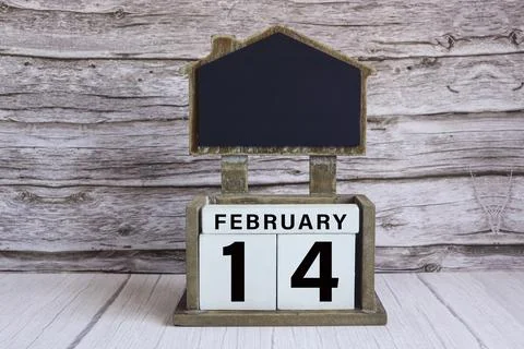 Chalkboard with date on white cube block on wooden table. Stock Photos