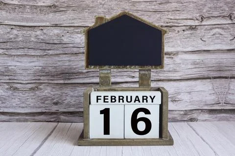 Chalkboard with date on white cube block on wooden table. Stock Photos