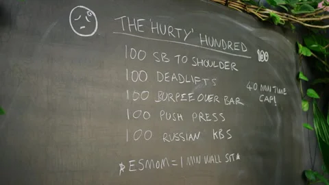 Chalkboard lists intense Hurty Hundred fitness challenge at scenic outdoor gym Stock Footage 281238124