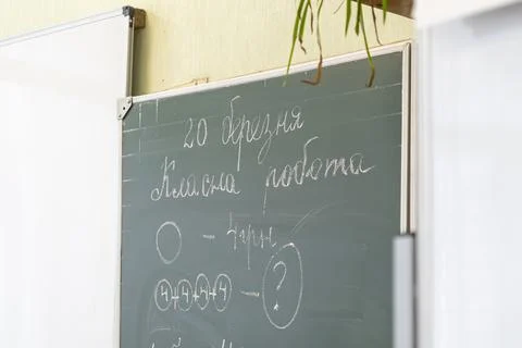 Chalkboard with math exercises in an elementary school classroom reflecting.. Stock Photos