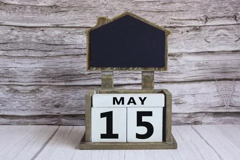 Chalkboard with May 15 date on white cube block on wooden table. Stock Photos