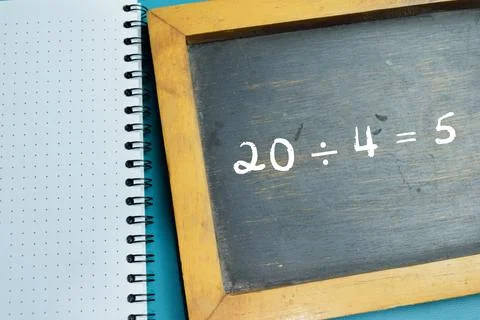 Chalkboard with phrase 20  4 = 5 math division equation on wooden desk. Stock Photos