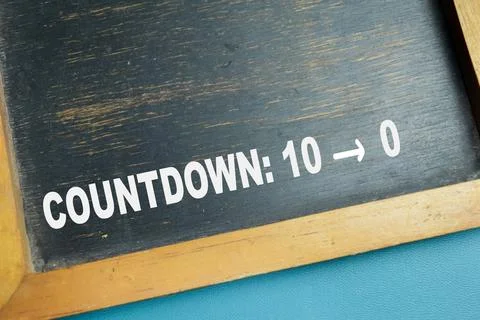 Chalkboard with phrase countdown from ten to zero on wooden desk. Stock Photos